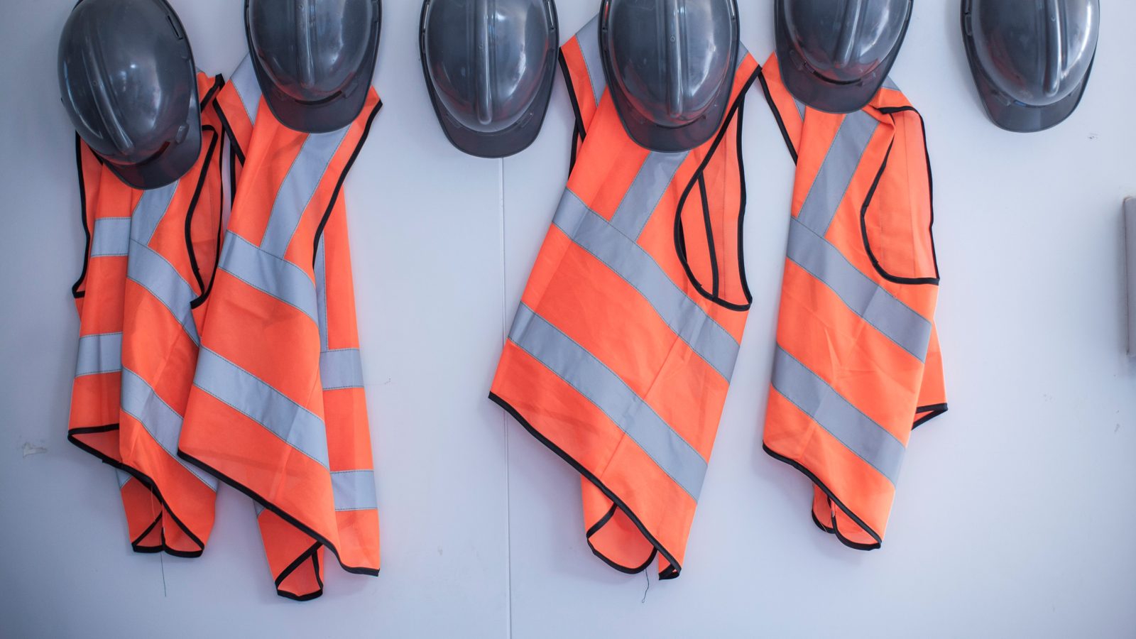 Safety jackets and hats hanging on pegs.